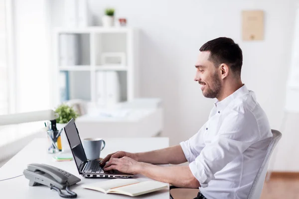 Gelukkig zakenman met laptop op kantoor — Stockfoto