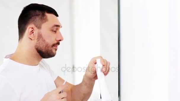 Hombre con cepillo de dientes limpieza de dientes en el baño — Vídeos de Stock
