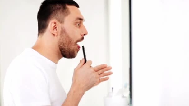 Man with comb looking to mirror and singing — Stock Video