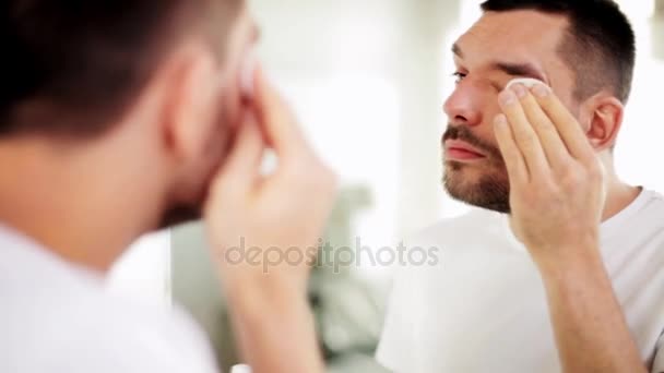 Homem com almofada de algodão limpeza rosto no banheiro — Vídeo de Stock