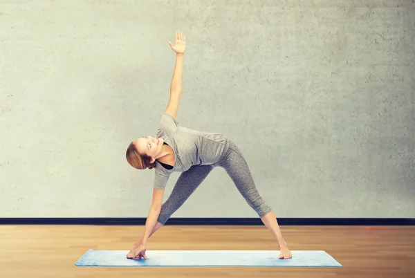 Vrouw maken yoga driehoek pose op de mat — Stockfoto