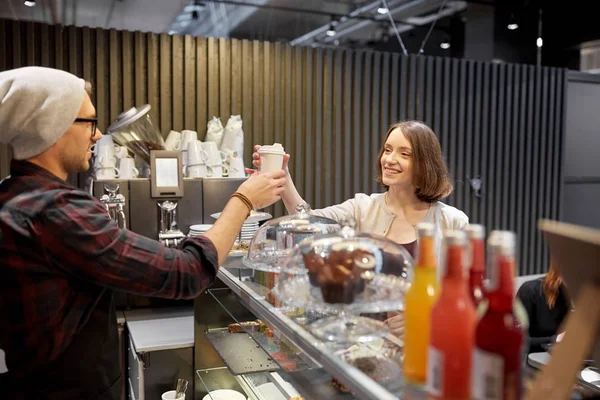 Seller giving coffee cup to woman customer at cafe — Stock Photo, Image
