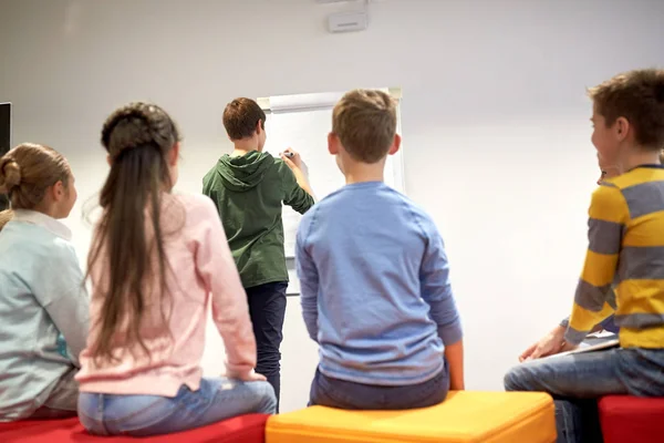 Student pojke med markör skriva på flip board — Stockfoto