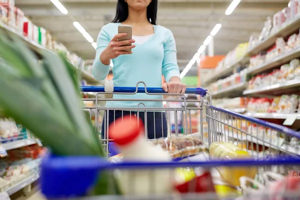 Kvinna med smartphone att köpa mat på stormarknad — Stockfoto
