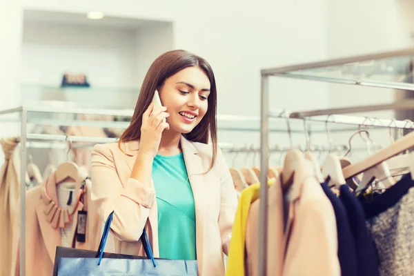 Gelukkig jonge vrouw kleding in winkelcentrum kiezen — Stockfoto