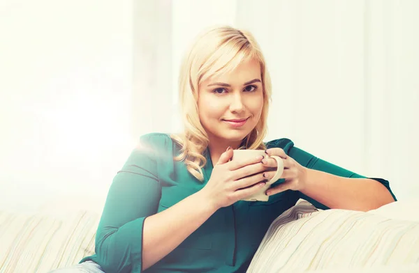 Glad kvinna med kopp te eller kaffe hemma — Stockfoto