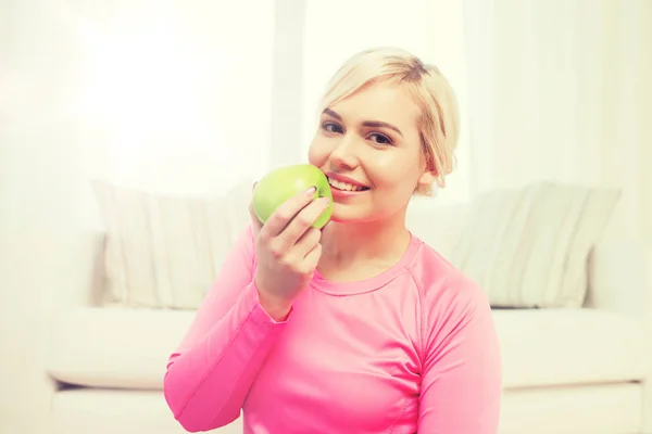 Mulher feliz comendo maçã em casa — Fotografia de Stock