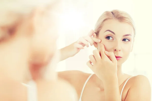 Mujer apretando espinilla en el espejo del baño — Foto de Stock