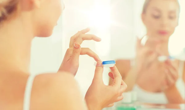 Mujer joven aplicando lentes de contacto en el baño —  Fotos de Stock