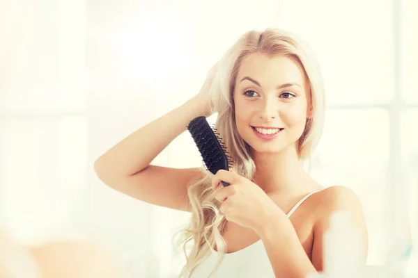 バスルームでコンブと幸せな女性ブラッシング髪 — ストック写真