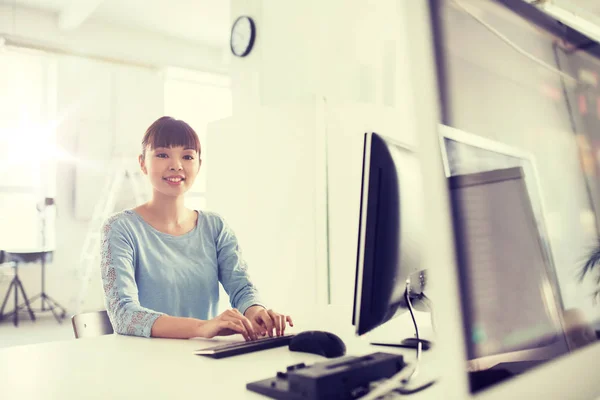 Счастливая азиатка с компьютером в офисе — стоковое фото