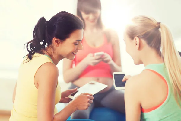 Gelukkig zwangere vrouwen met gadgets in sportschool — Stockfoto