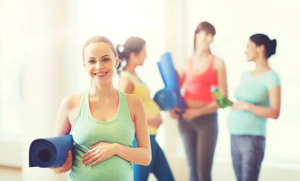 Mujer embarazada feliz con estera en el gimnasio —  Fotos de Stock