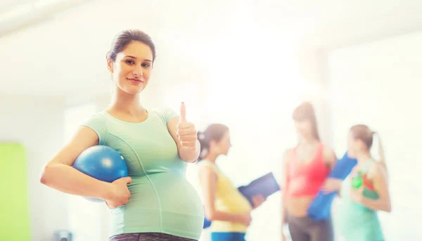 Těhotná žena s míčem v tělocvičně ukazuje palec — Stock fotografie