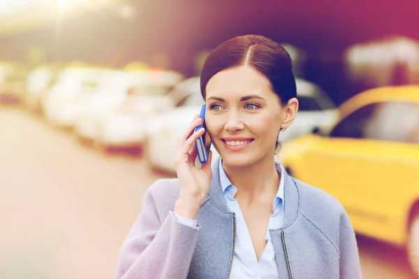 Smiling woman with smartphone over taxi in city — Stock Photo, Image