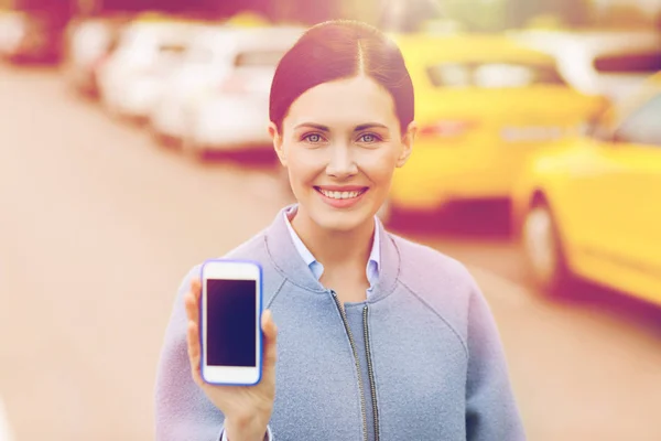 Lachende vrouw met smartphone over taxi in stad — Stockfoto