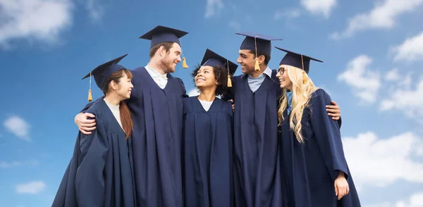 Gelukkig studenten of bachelors over blauwe hemel — Stockfoto