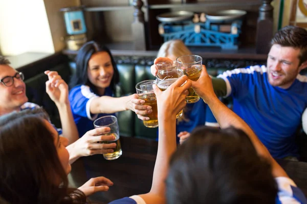 Fãs de futebol clinking copos de cerveja no bar esporte — Fotografia de Stock