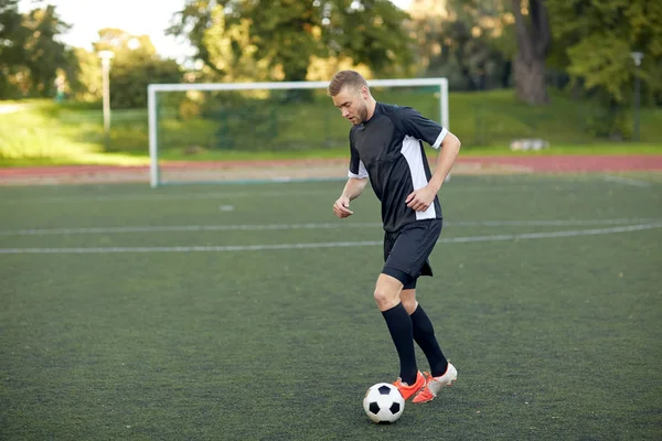 Voetbalspeler met bal op voetbalveld spelen — Stockfoto