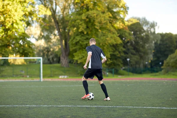 Voetbalspeler met bal op voetbalveld spelen — Stockfoto