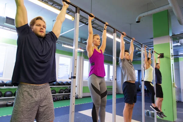 Grupp människor hänger på horisontell bar i gymmet — Stockfoto