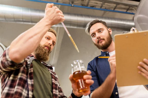 Мужчины с пипеткой тестируют пиво на пивоварне — стоковое фото
