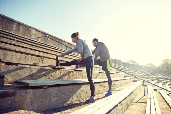 Paar stretching been op stands van stadion — Stockfoto