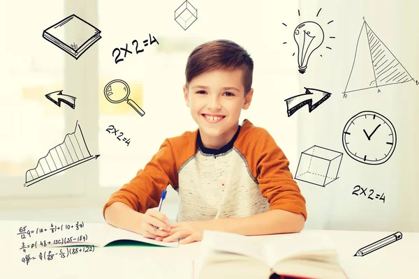 Leende student pojke skriva till anteckningsbok hemma — Stockfoto
