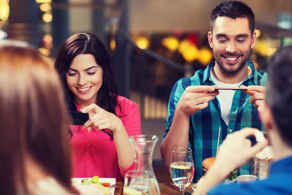 Glada vänner tar bild av mat på restaurang — Stockfoto