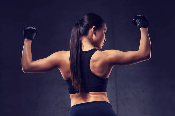 Jovem mulher flexionando músculos no ginásio — Fotografia de Stock