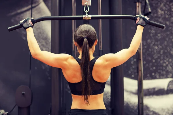 Mujer flexionando los músculos en la máquina de cable en el gimnasio —  Fotos de Stock