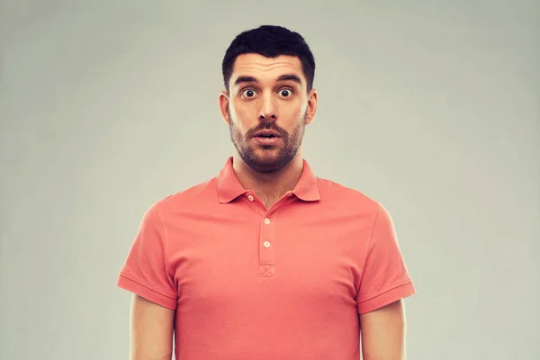 Uomo sorpreso in polo t-shirt su sfondo grigio — Foto Stock