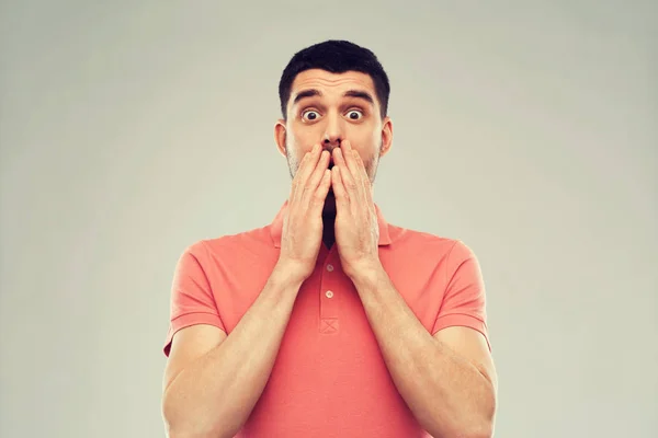 Verängstigter Mann im Polo-T-Shirt vor grauem Hintergrund — Stockfoto