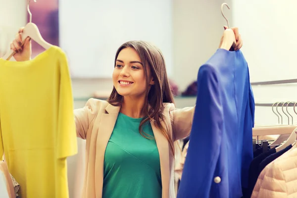 Heureux jeune femme choisir des vêtements dans le centre commercial — Photo