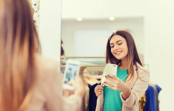 Mujer tomando selfie espejo por teléfono inteligente en la tienda —  Fotos de Stock