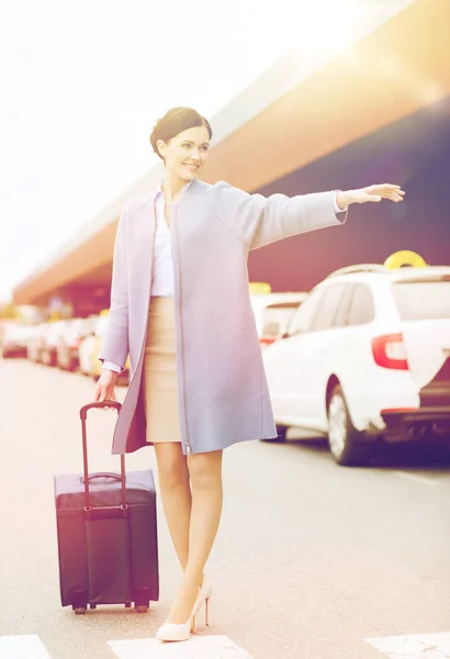 Sorridente giovane donna con borsa da viaggio cattura taxi — Foto Stock