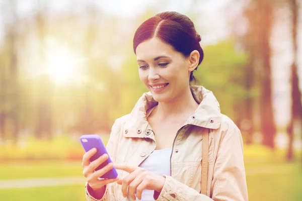 Leende kvinna ringer på smartphone i park — Stockfoto