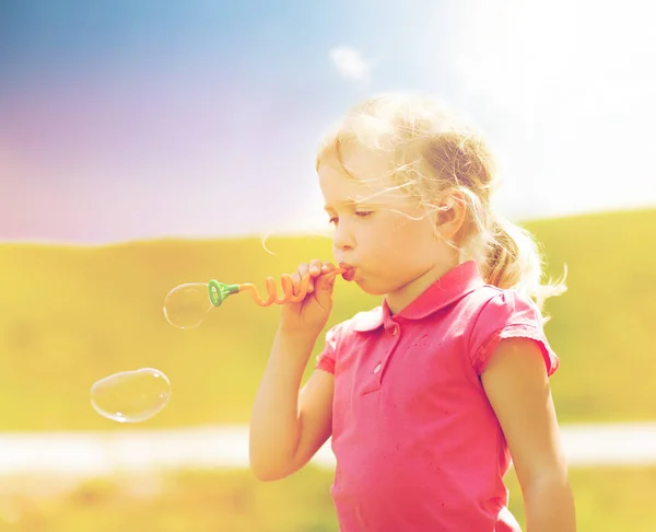 Little girl blowing soap bubbles outdoors — Stock Photo, Image