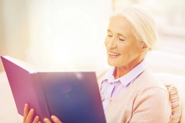 Szczęśliwy uśmiechający się starszy kobieta czytania książki w domu — Zdjęcie stockowe
