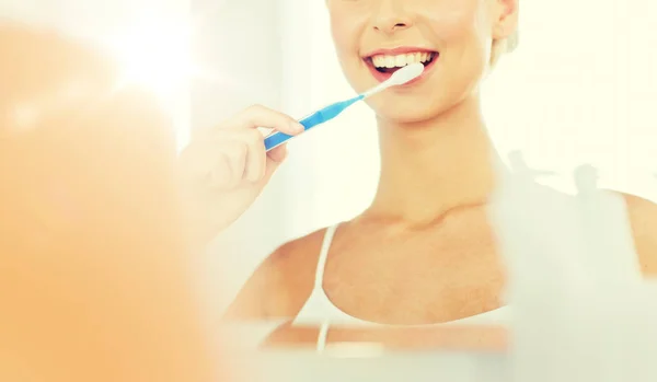 Mulher com escova de dentes limpeza dentes no banheiro — Fotografia de Stock