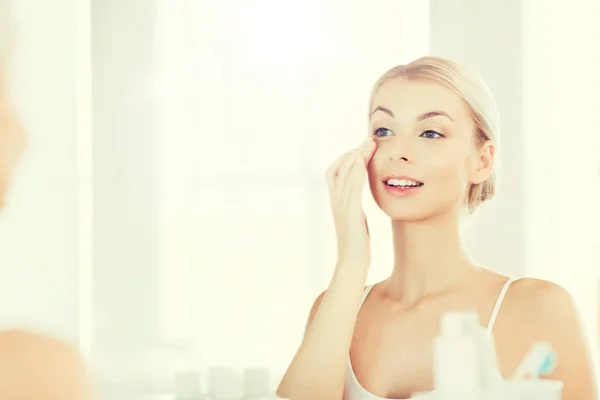Šťastná žena použitím krém čelit v koupelně — Stock fotografie