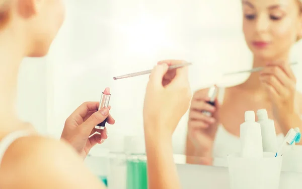 Wanita dengan lipstik dan make up kuas di kamar mandi — Stok Foto