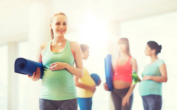 Mujer embarazada feliz con estera en el gimnasio — Foto de Stock