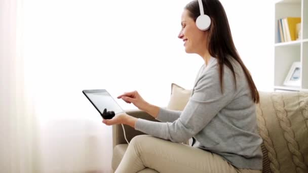 Mujer feliz con tablet pc y auriculares en casa — Vídeo de stock