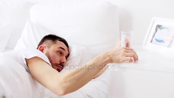 男は目を覚ます、自宅のベッドで水を飲む — ストック動画