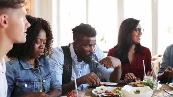 Щасливі друзі їдять і розмовляють в ресторані — стокове відео