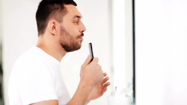 Man with comb looking to mirror and singing — Stock Video