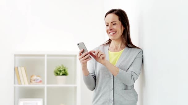 Mulher feliz mensagem de texto no smartphone em casa — Vídeo de Stock