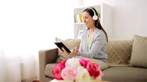 Mulher feliz com tablet pc e fones de ouvido em casa — Vídeo de Stock