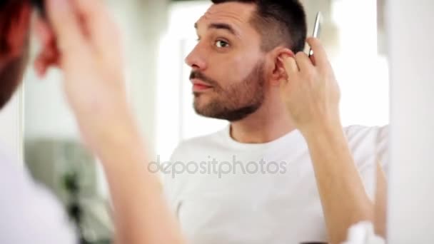 Happy man brushing hair with comb at bathroom — Stock Video